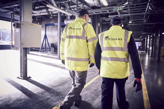 Two Equans workers in a high visability from the back
