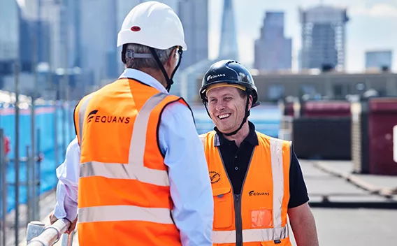 Two Equans employees on a building roof in PPE