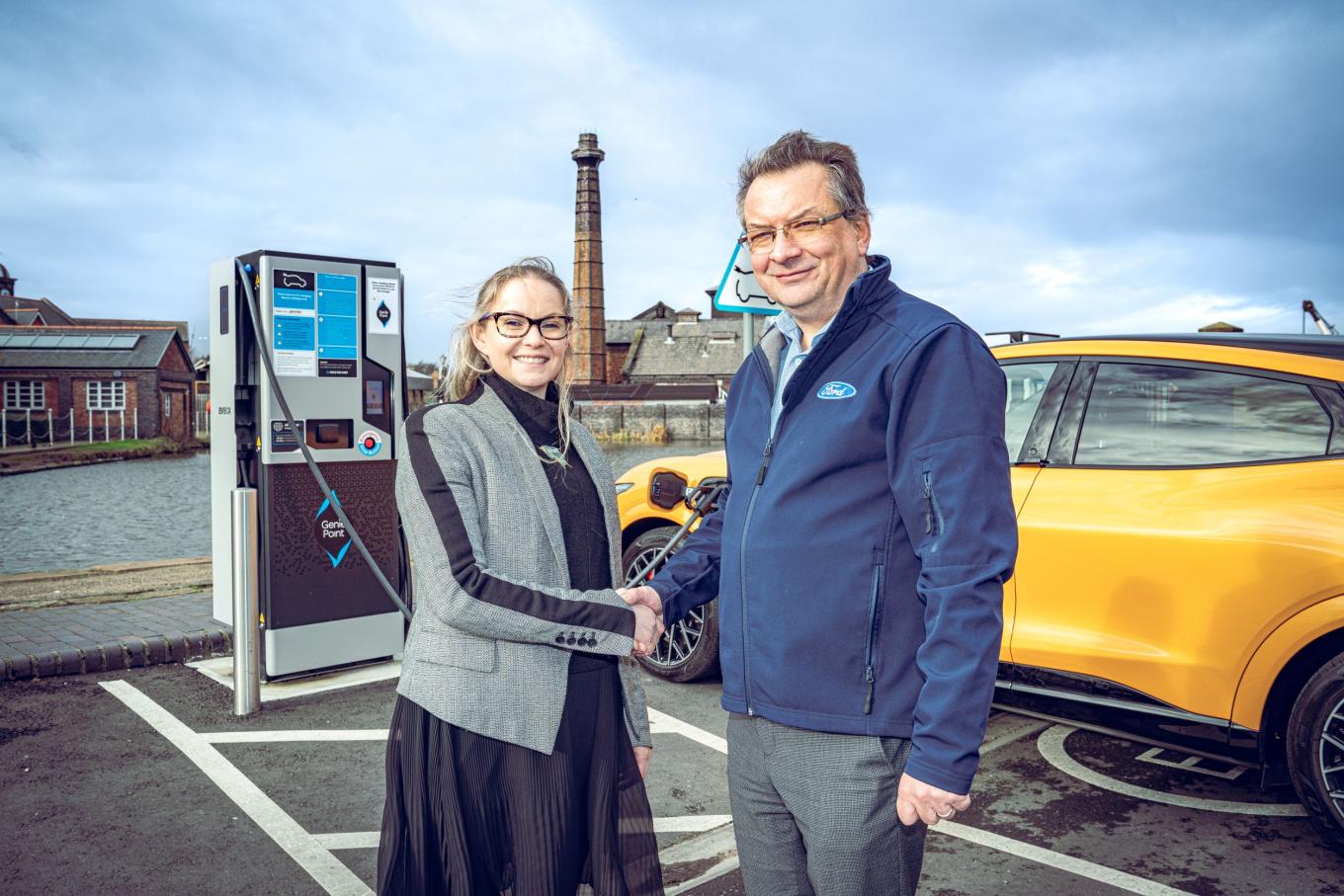 Dee Humphries of Equans and customer at Ford shaking hands in front of EV charger