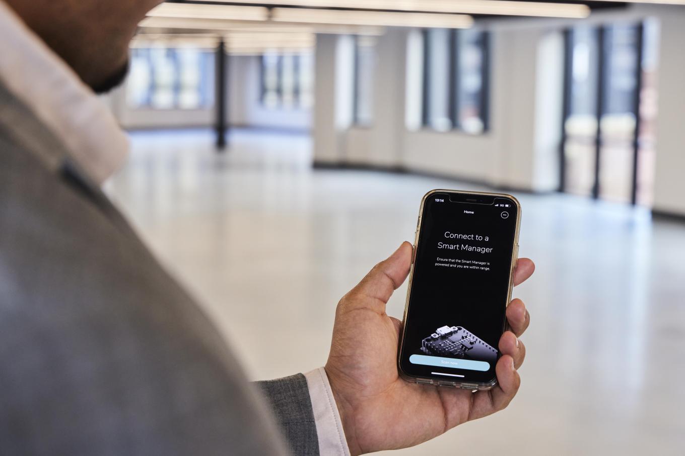 Stock image of a man holding his phone, using a smart management office app