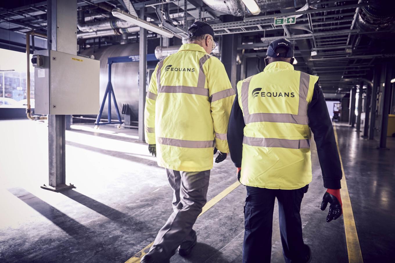 Two Equans workers in a high visability from the back