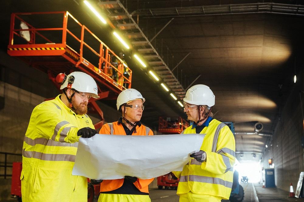 employees reviewing plans in road tunnel