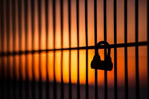 Padlock on fence with red sky