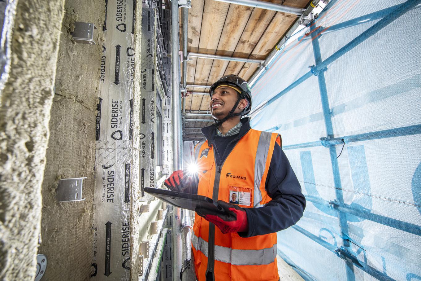 Equans employee surrounded by scaffolding and undertaking retrofit assessments