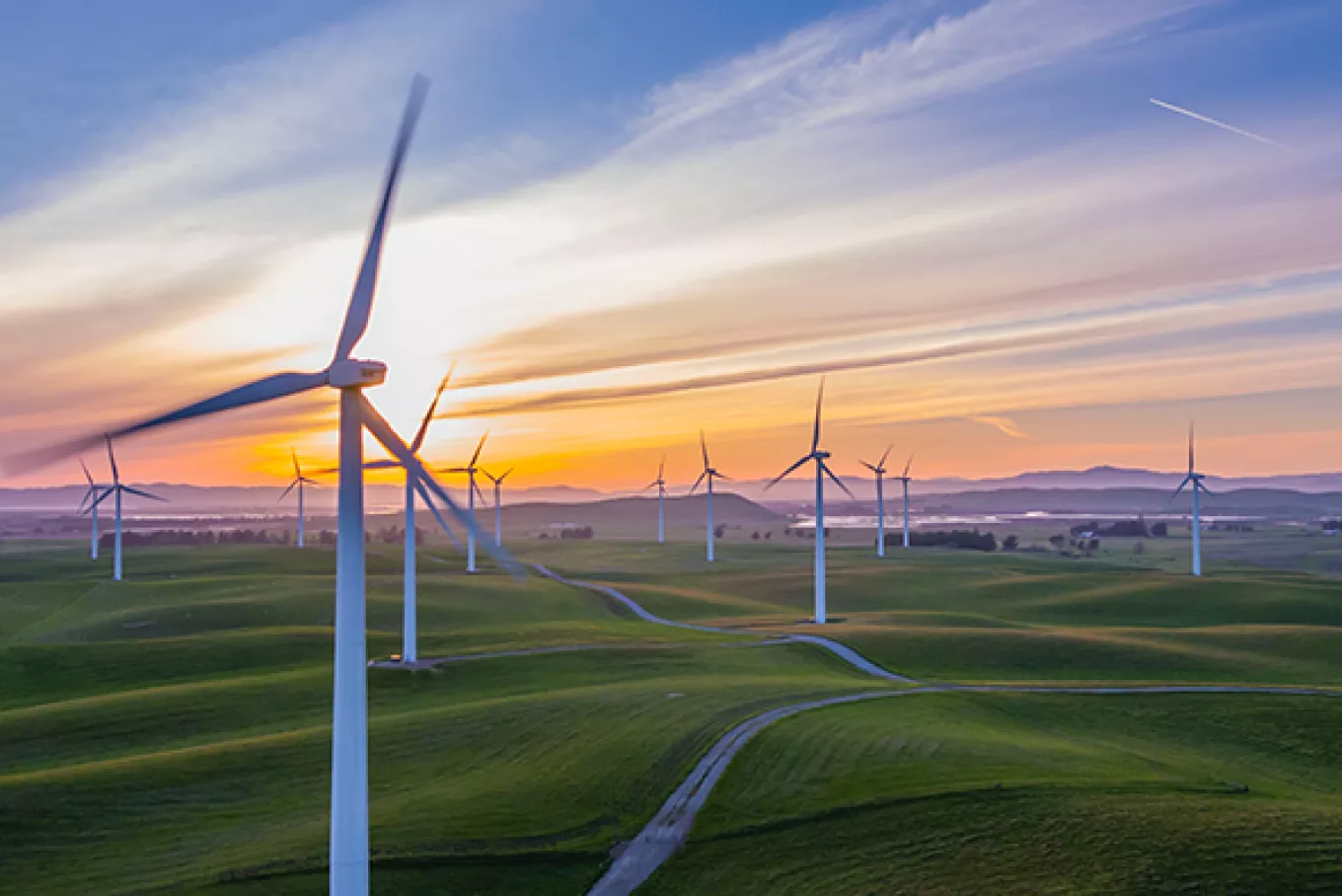 Several wind turbines set in a field at sunset