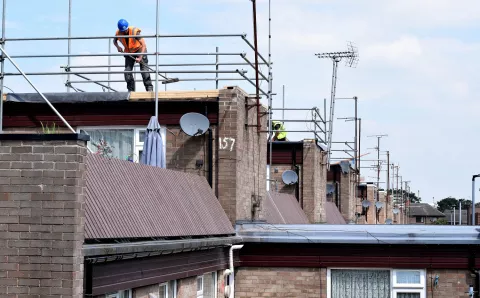Worker with hard hat, high vis on housing development roofs
