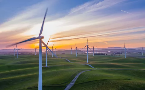 Several wind turbines set in a field at sunset