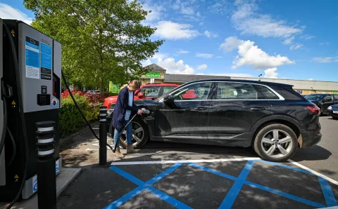 A lady charging her EV at a genie point charger in ASDA