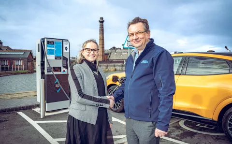 Dee Humphries of Equans and customer at Ford shaking hands in front of EV charger