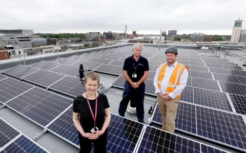 Equans employees stood on Newcastle Central Library roof next to roof top solar