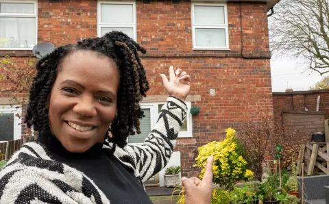 A lady standing in front of a house with solar panels in Erdington