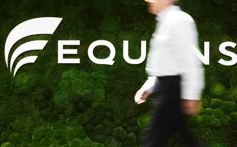 A gentleman walking past an Equans entrance sign