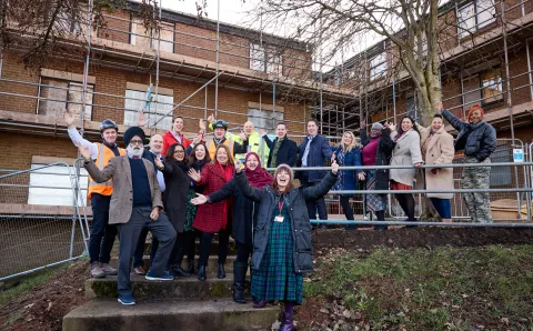 Staff from Equans and St Basil's celebrating the start of work in front of scaffolding
