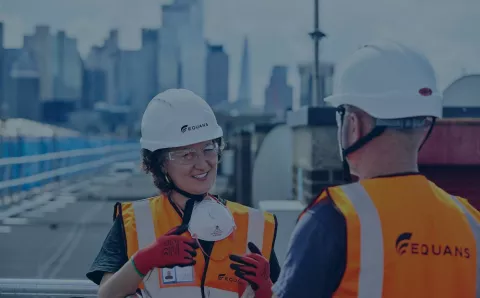 Female Equans employee speaking to male Equans employee on roof