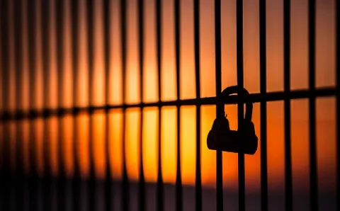 Padlock on fence with red sky