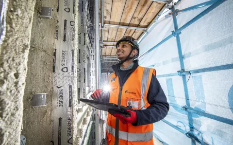Equans employee surrounded by scaffolding and undertaking retrofit assessments